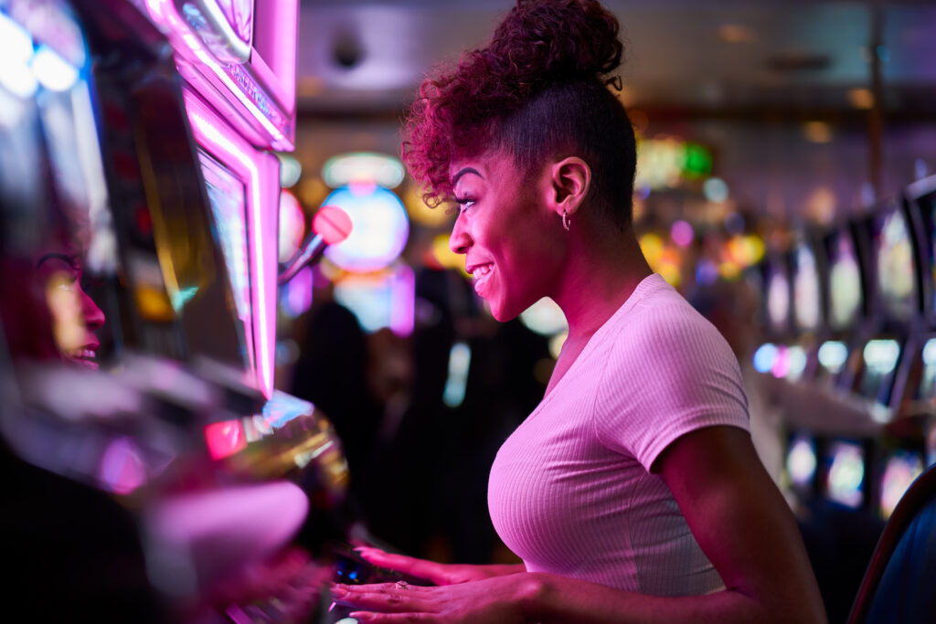 A photo of a woman playing a slot machine in a casino.