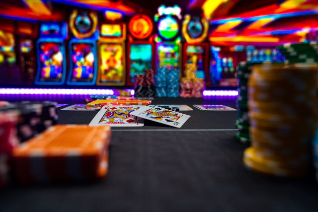 A photo of cards on a poker table with slot machines in the background.