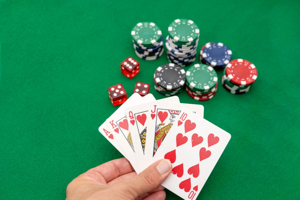 A photo of a person holding a Royal Flush with casino dice and chips in the background.