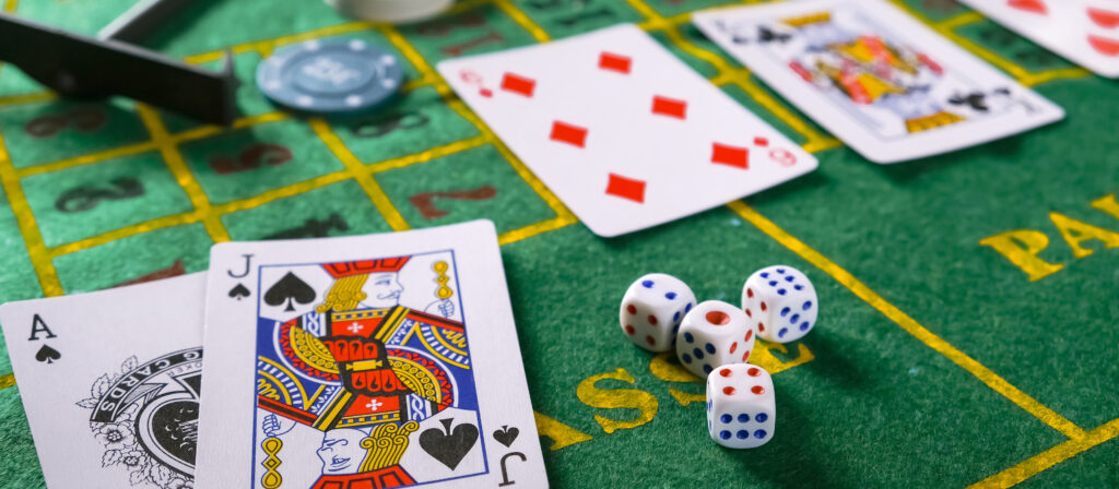 A photo of multiple playing cards and dice on a casino table.