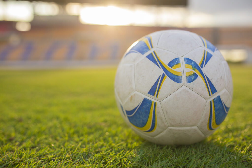 A close up photo of a football with a football stadium in the background.