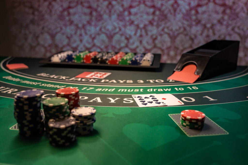 Close up of a casino blackjack table with stacks of casino chip and playing cards on it.