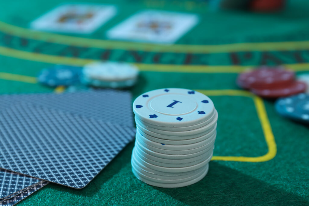 Close up of a stack of casino chips beside some playing cards on a blackjack table.