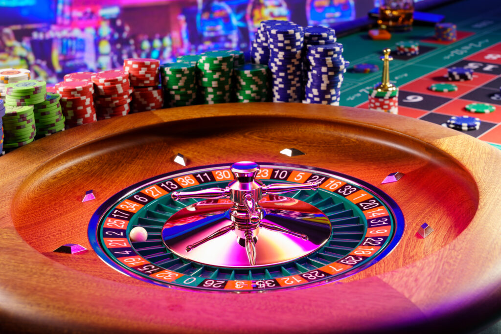 Close up of a roulette wheel at a casino with stacks of casino chips beside it.
