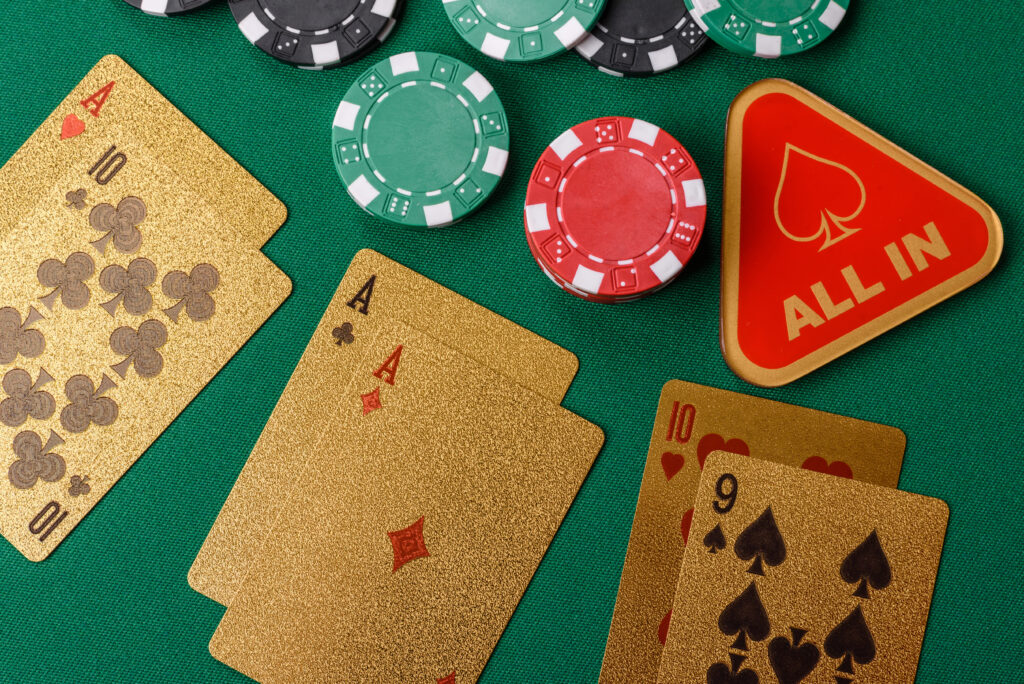 Playing cards, casino chips, and a triangular block with "All In" on it on a green background.